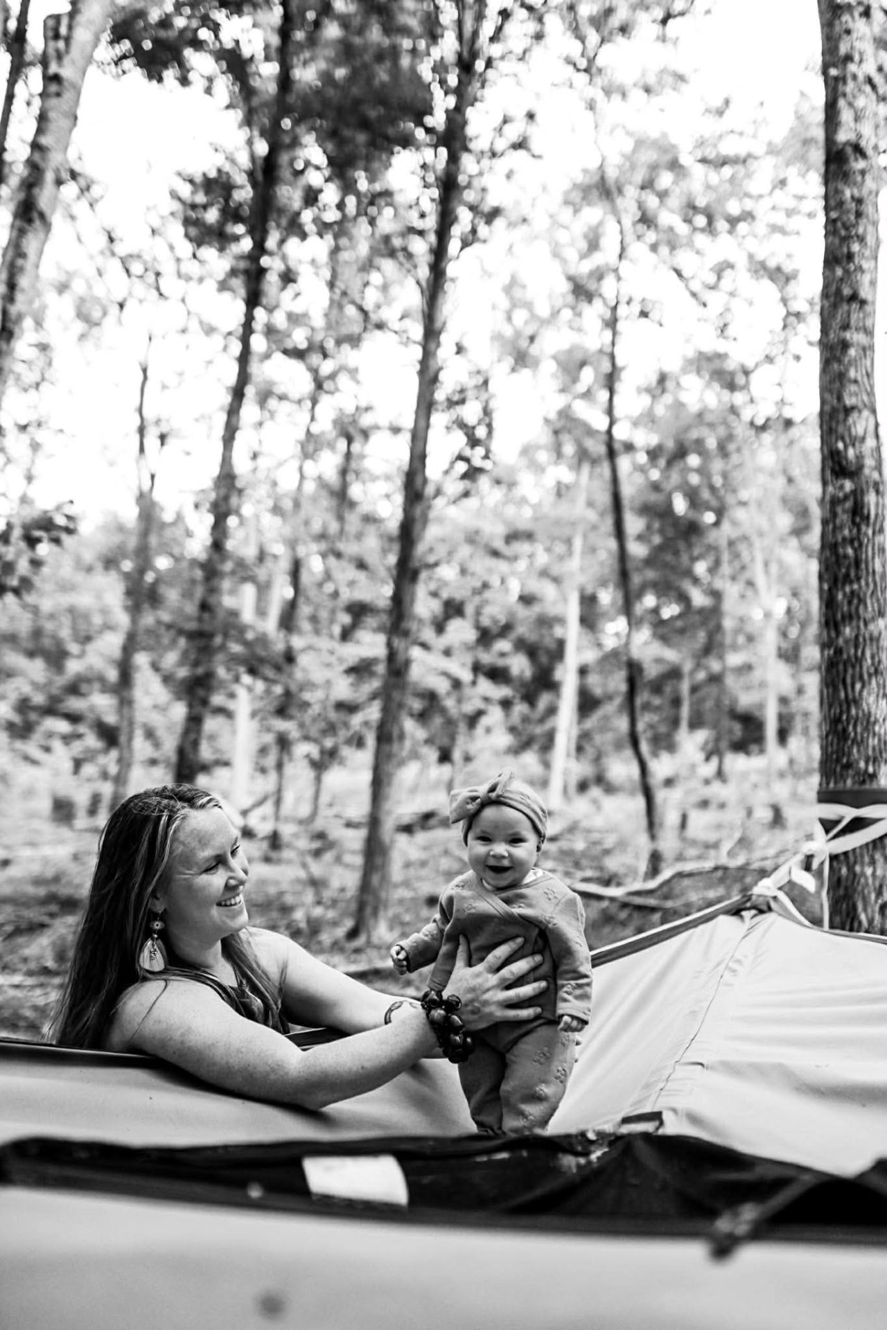 A mother and baby sharing laughter in the woods