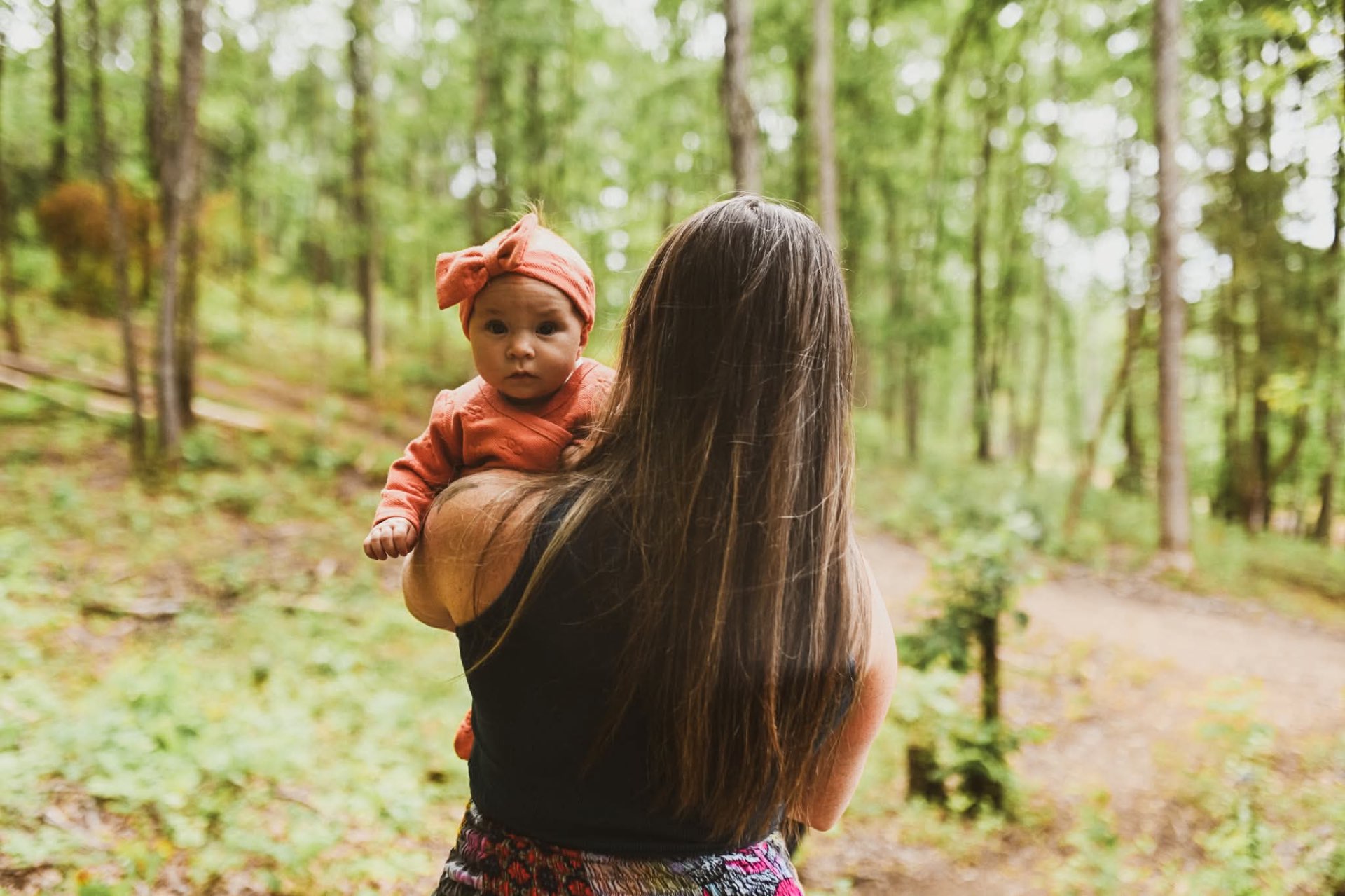 A mother carrying her baby through the forest path